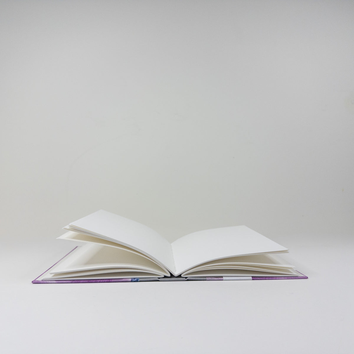 Handmade book standing upright, showing paste paper cover and blank text block
