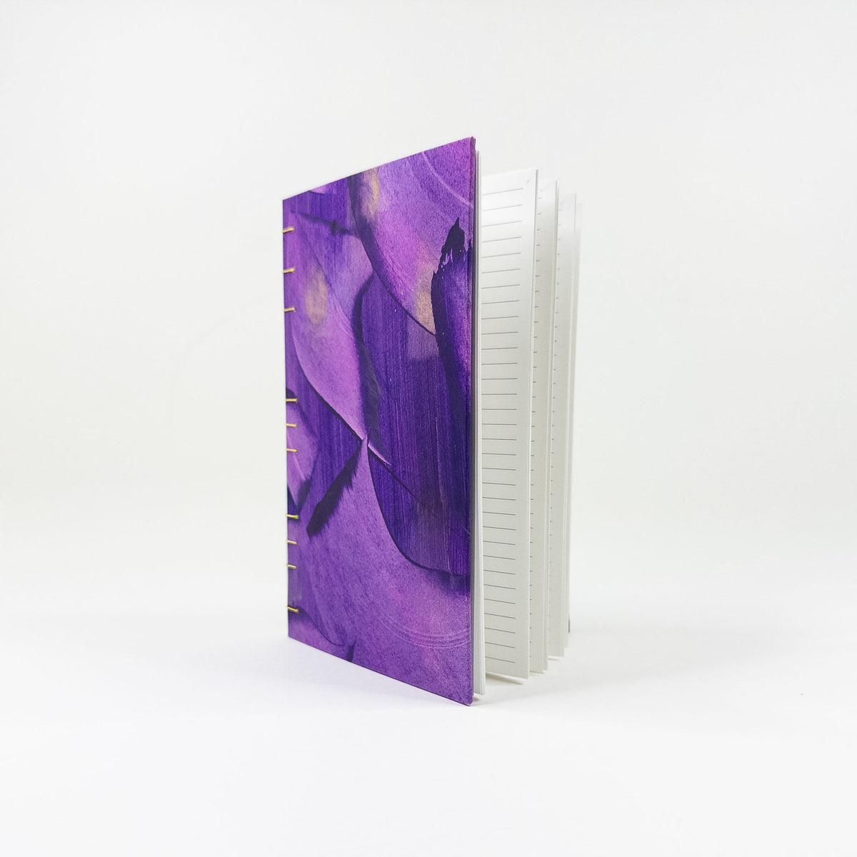 Open handmade book lying flat, showing lined pages and gold spine stitching