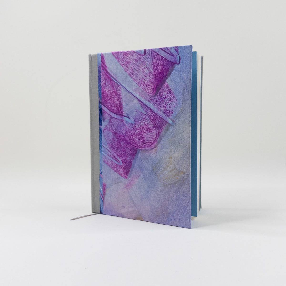 Handmade journal standing upright, showing teal endpapers and blank text block