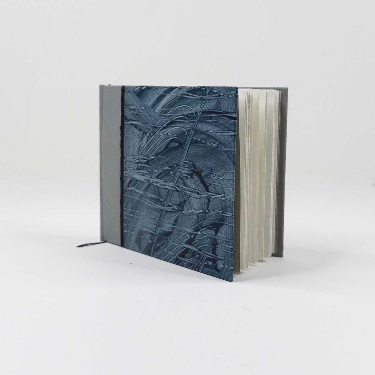 Landscape handmade journal standing upright, showing lined pages and grey cloth spine