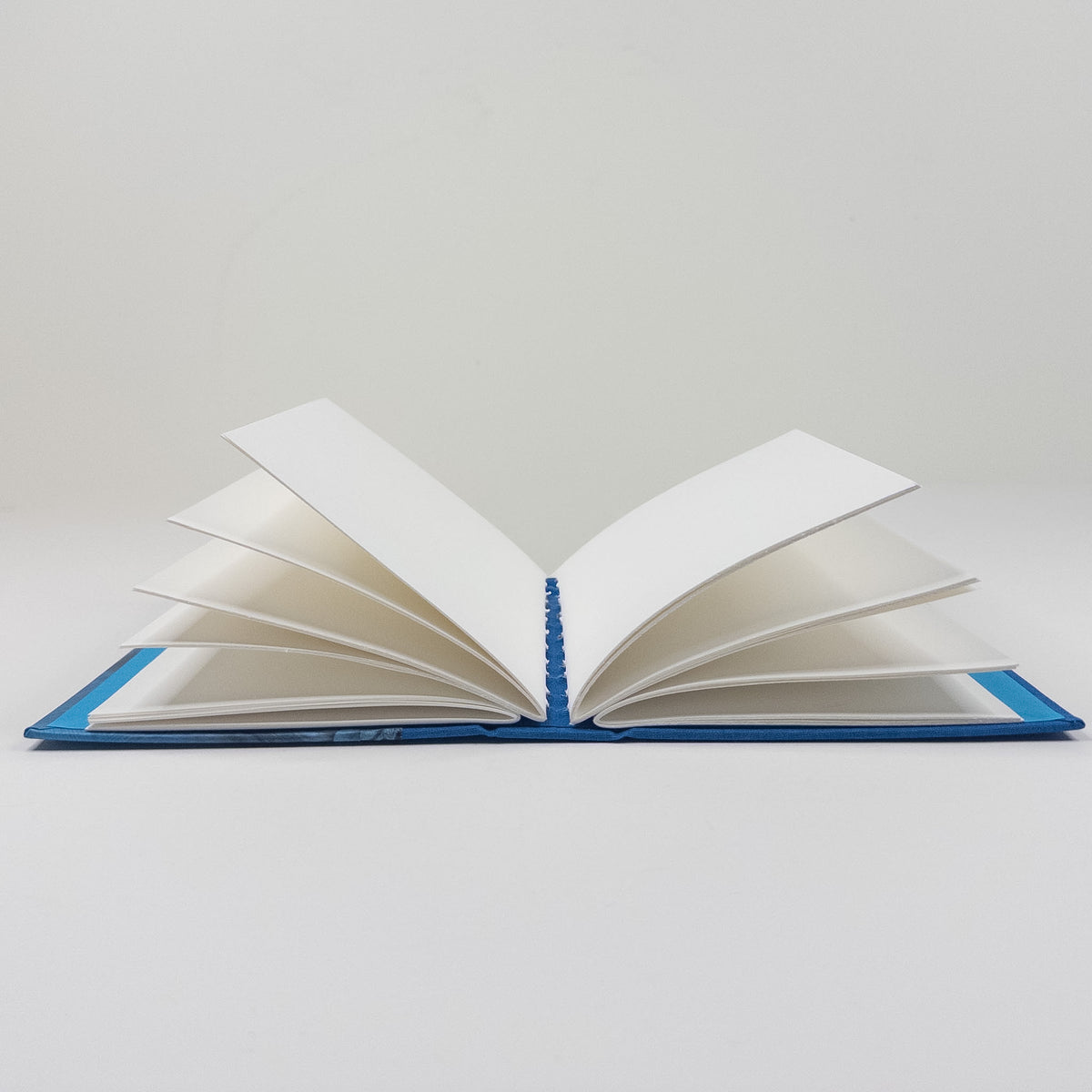 Handmade book standing upright, showing paste paper cover and blank text block
