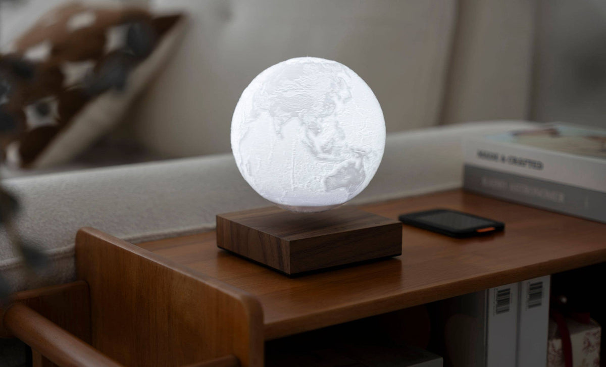 The unlit globe floating above its wooden base on a side table in daylight