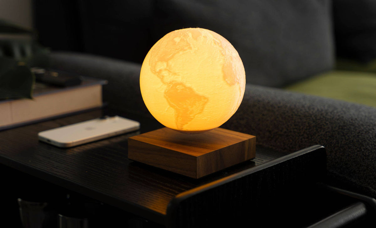 The lit globe floating above its base on a wooden table, a sofa behind it