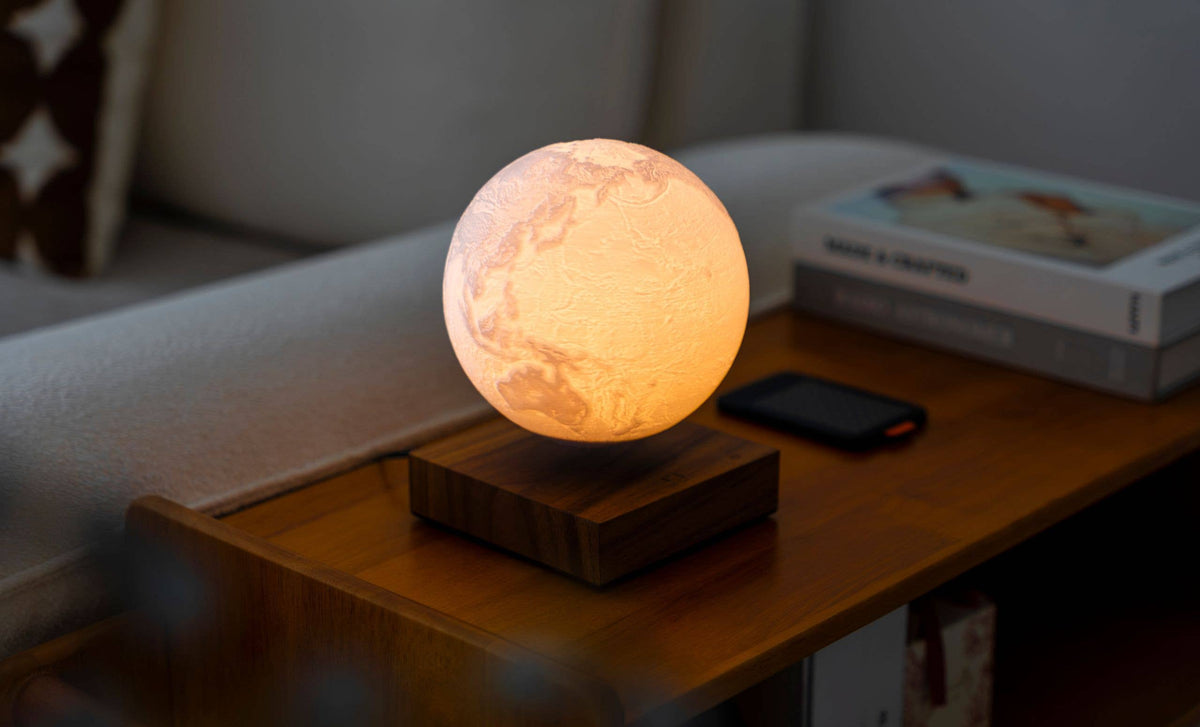 The globe glowing softly on a coffee table beside a stack of books