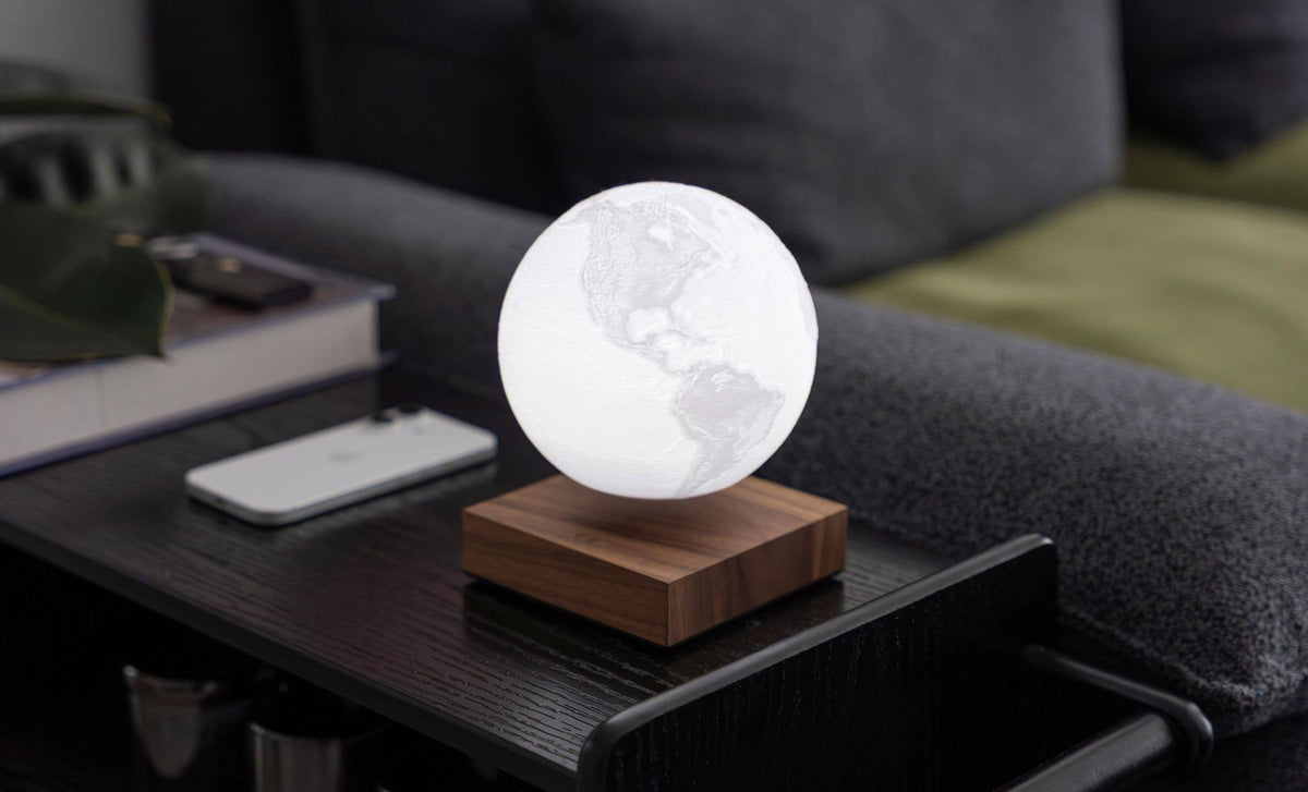 The globe unlit, showing its pale printed surface, floating above the base on a side table