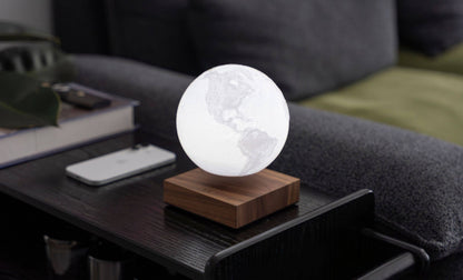 The globe unlit, showing its pale printed surface, floating above the base on a side table